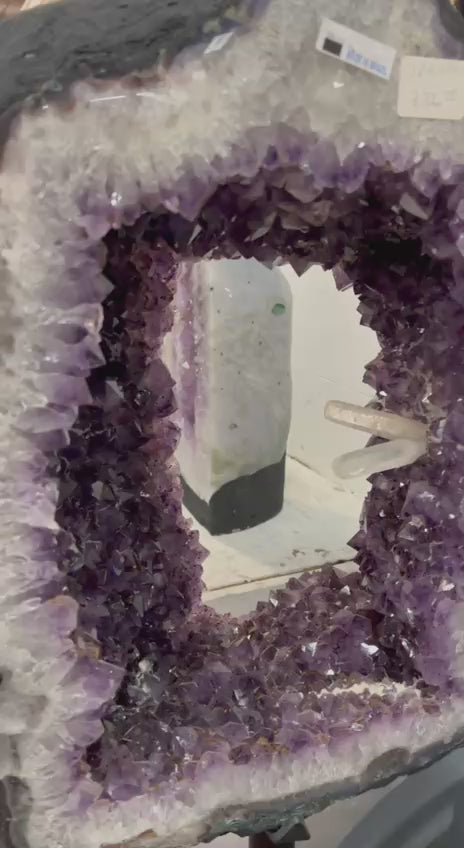 Beautiful Geode cut with clusters and points inside the amethyst tower on stand – video